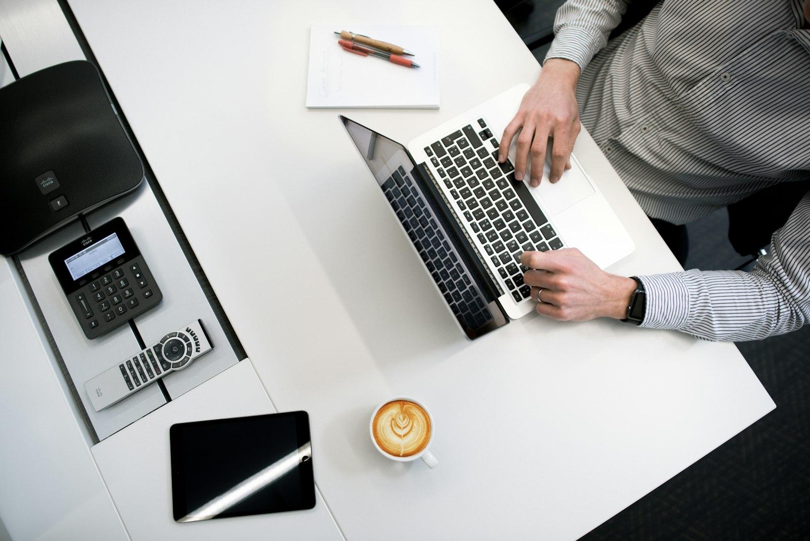 A laptop and a phone side by side on one desk, the same product open on both