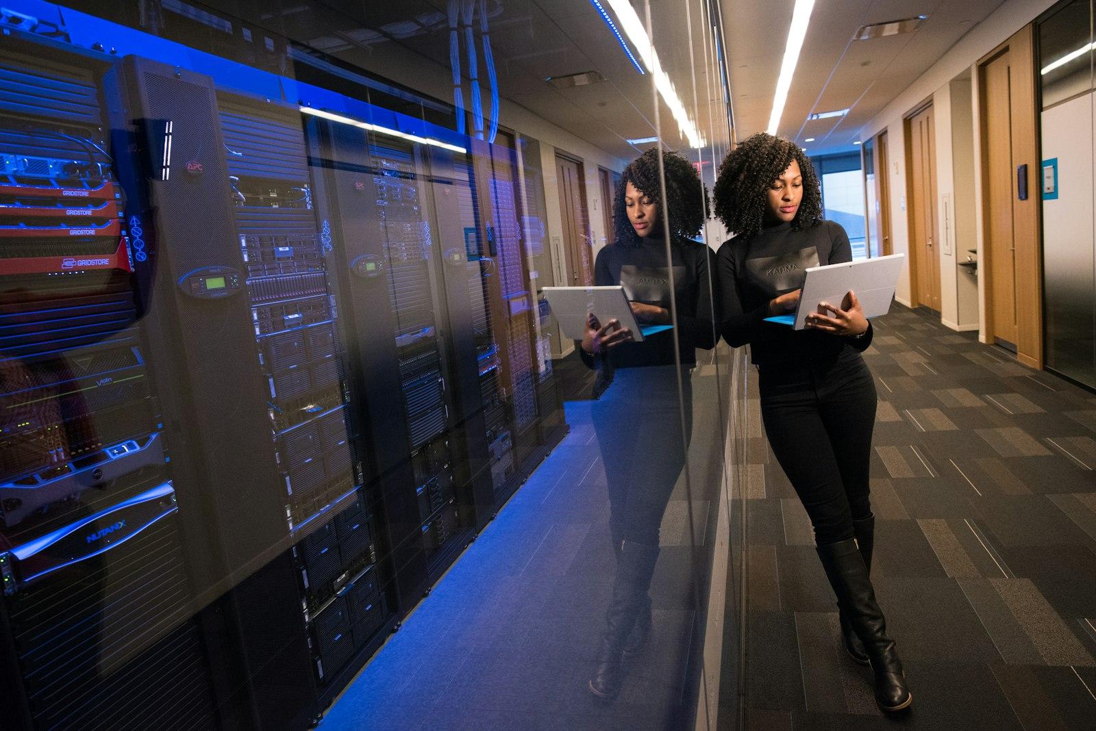 An engineer walking through a server room with a laptop