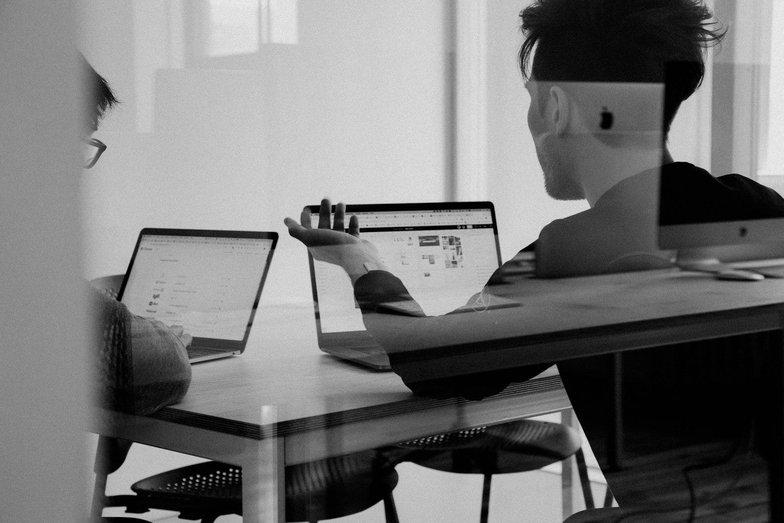 Two people reviewing work together at a glass table